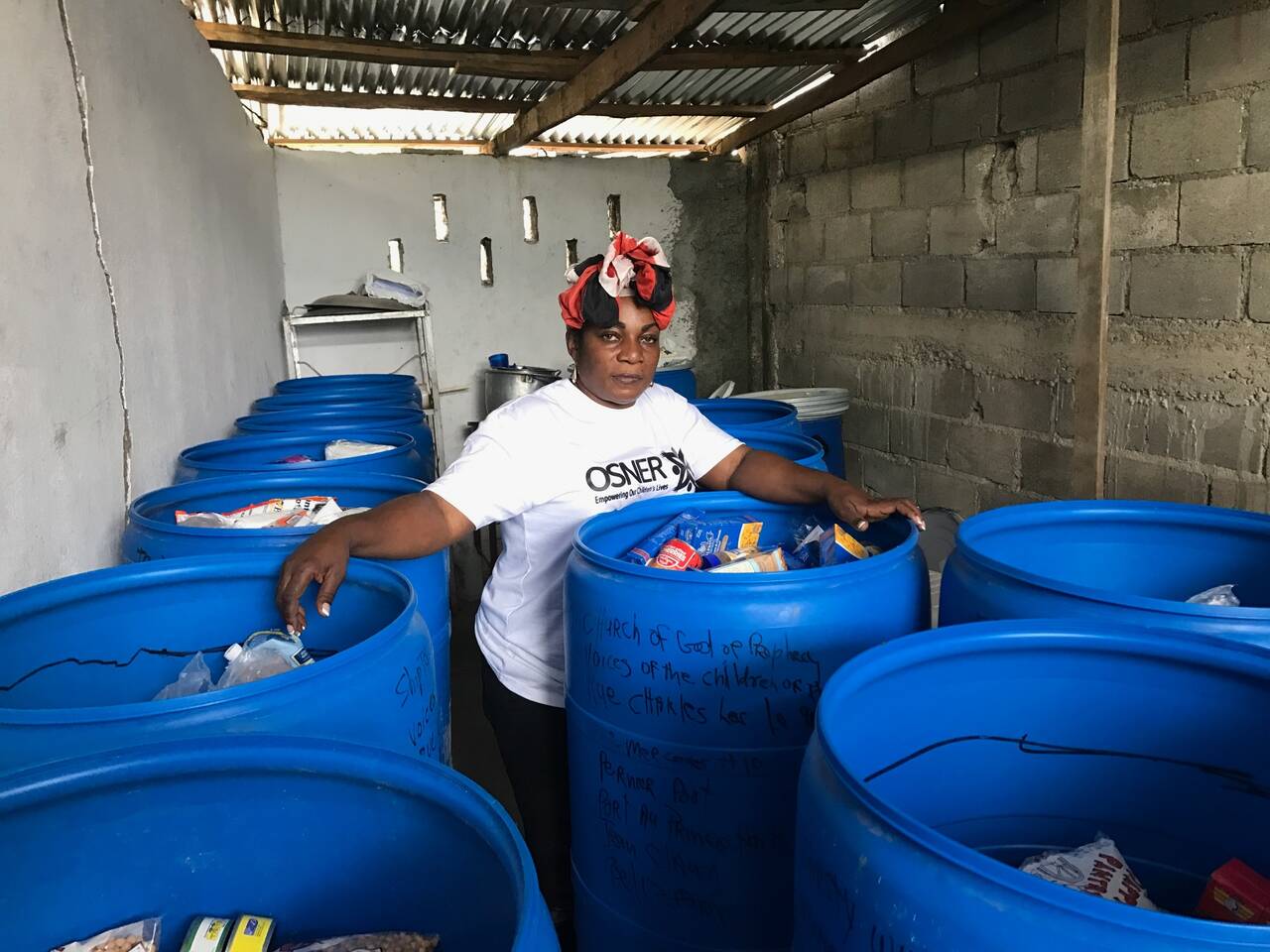 Sister leader standing among barrels of supplies prepared for shipment to Haiti